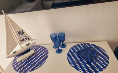 a table with two blue glasses and a toy boat at Onda blu in Carini