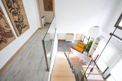 a staircase in a home with wooden floors and a yellow chair at iFlat Corte Seralcadi in Palermo
