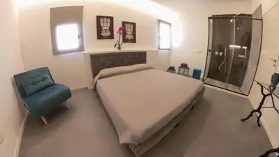 a bedroom with a bed and a shower and a blue chair at Casa Degli Aragonesi in Palermo