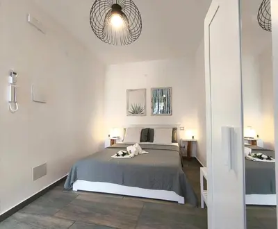 a white bedroom with a bed and two lamps at Casa vacanze green house in Terrasini