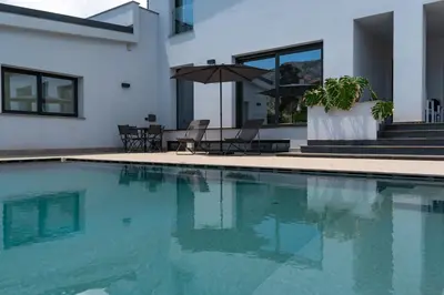 a swimming pool with chairs and an umbrella next to a house at Villa Tina Mondello in Mondello