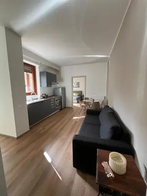 a living room with a black couch and a kitchen at LaPignaVerde Suites in Palermo