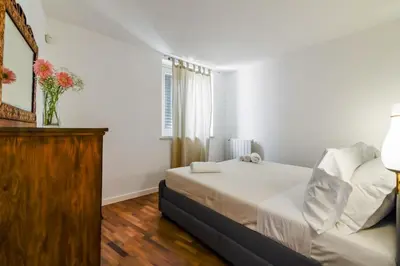 a white bedroom with a bed and a vase of flowers at GuestHost - Vucciria & La Cala Lovely Apartment with Terrace in Palermo