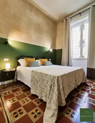 a bedroom with a large bed in a green wall at Donna Oliva Guest House in Palermo