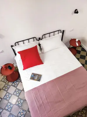 a bedroom with a bed with a red pillow at Donna Oliva Guest House in Palermo