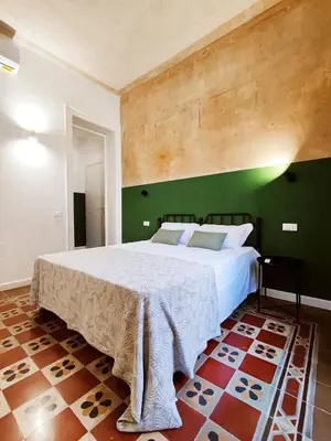 a bedroom with a large bed with a green wall at Donna Oliva Guest House in Palermo