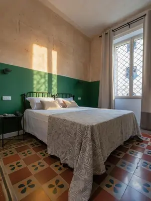 a bedroom with a large bed with a green wall at Donna Oliva Guest House in Palermo