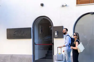 a man and a woman standing outside a building with their luggage at La Dimora dei Paladini in Bagheria