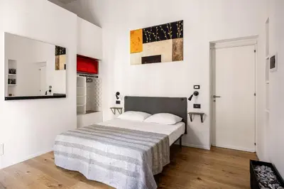 a white bedroom with a bed with a striped blanket at Azizò, la Gialla in Palermo