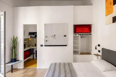 a white room with a bed and a kitchen at Azizò, la Gialla in Palermo