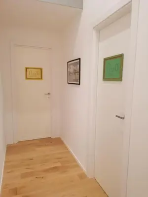 a room with white walls and wooden floors and two pictures on the wall at Azizò, la Verde in Palermo