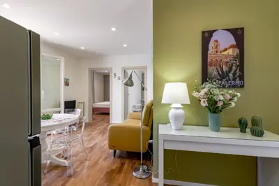 a living room with green walls and a table with flowers at GuestHost - Palermo's Rooftop - Apt with Panoramic Terrace in Palermo