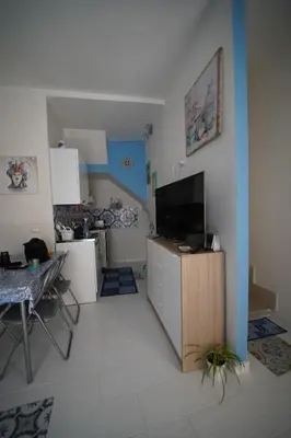 a living room with a television and a table and a kitchen at Casa di via Sole in Castellammare del Golfo