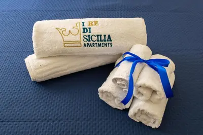 a towel with a blue ribbon sitting on a bed at I RE di SICILIA 2 in Palermo