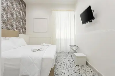 a white bedroom with a bed and a flat screen tv at Aragona House in Palermo