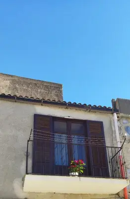 a building with a balcony with flowers on it at B&b da Ely in Ventimiglia di Sicilia
