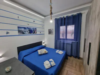 a bedroom with a blue bed and a table at Vida Loca -Appartamento vicino aereporto e 200mt spiaggia in Carini