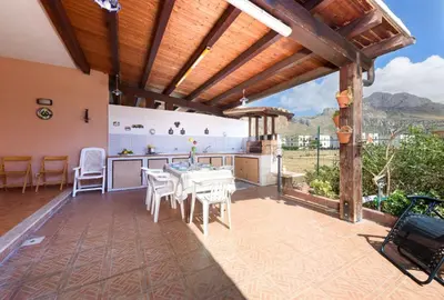 an outdoor patio with a table and a kitchen at I Tre Golfi - Pianeti in San Vito lo Capo