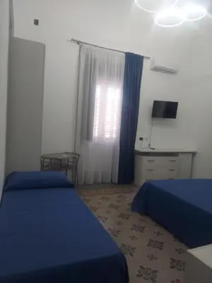 a bedroom with two beds and a desk and a window at Guest House Militello in Palermo