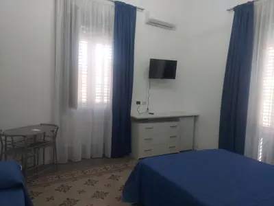a bedroom with a blue bed and a dresser and windows at Guest House Militello in Palermo