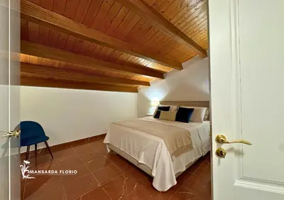a bedroom with a bed and a wooden ceiling at Mansarda Florio in Palermo