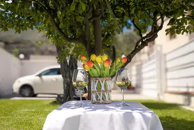 two glasses of wine and a vase of flowers on a table at Casa vacanze Casuzza Sferracavallo Palermo in Palermo
