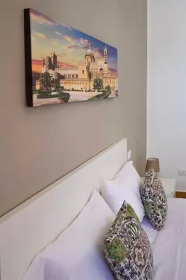 a white bed with two pillows and a painting on the wall at Casa vacanze Casuzza Sferracavallo Palermo in Palermo