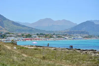 a group of people standing on a beach near the water at La Casetta di Ale in Isola delle Femmine