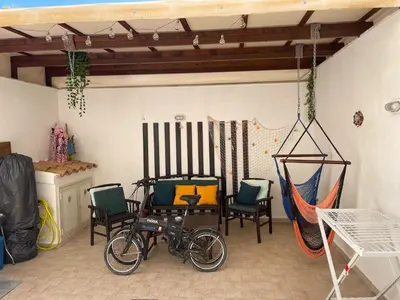 a bike parked in a room with chairs and a hammock at Casa Joe in San Vito lo Capo