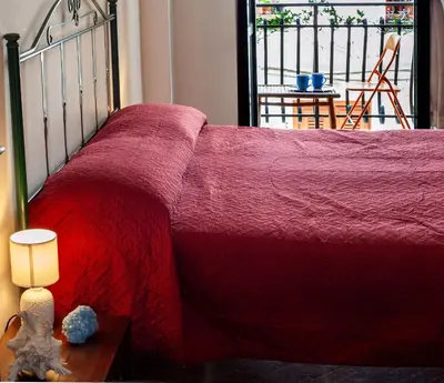 a bed with a red blanket and a table with a lamp at Casa del Blu in Palermo
