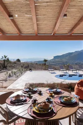 a wooden table with plates of food on it at Villa Eos con piscina privata in Scopello