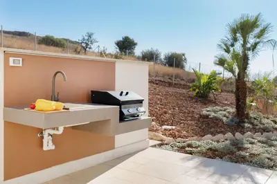 a outdoor kitchen with a sink and a grill at Villa Eos con piscina privata in Scopello