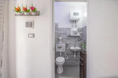 a bathroom with a toilet and a sink with flowers at La Casa di Sciù Sciù in Palermo