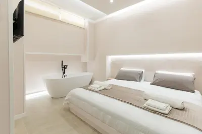 a white bedroom with a large bed and a bath tub at Ambrosia Suite in Palermo