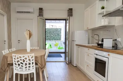 a kitchen with a table and chairs and a kitchen with white cabinets at Ludo Holiday House - Charming con patio a due passi dalla cattedrale in Palermo