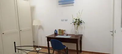 a desk with a blue chair and a vase of flowers at Casa Renda in Balestrate