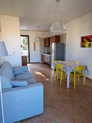 a living room and kitchen with a blue couch and a table at Triskelia in San Vito lo Capo