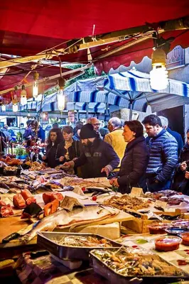 a group of people standing around a market with food at La Terrazza di Massimo in Palermo
