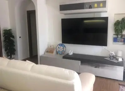 a living room with a white couch and a flat screen tv at Mondello House Lemon in Palermo