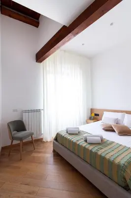 a bedroom with a bed and a chair and a window at Lùlom - Rooftop Boutique Rooms in Palermo