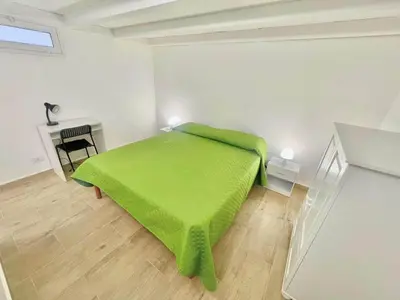 a bedroom with a green bed and a desk at Alloggio delle Carrozze al Ballarò in Palermo