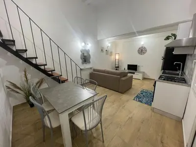 a kitchen and a living room with a table and chairs at Alloggio delle Carrozze al Ballarò in Palermo