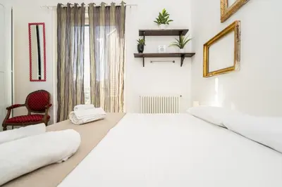 a white bedroom with a large bed and a chair at Maison d'art Orleans in Palermo