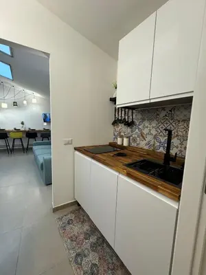a kitchen with white cabinets and a living room at ArcorosaApartment Palermo Centro in Palermo