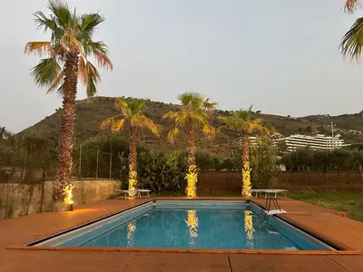 a swimming pool with palm trees and a mountain at Sunset Holiday House in Cefalù