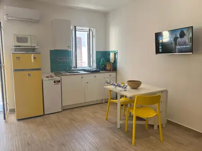 a kitchen with yellow chairs and a table and a refrigerator at Home al Capo by Holiday World in Palermo