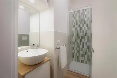 a bathroom with a sink and a glass shower at Anna's Central Apartment in Palermo