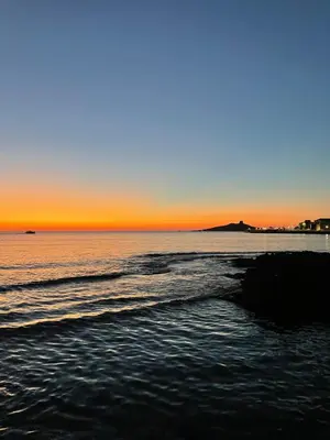 a beach with the sun setting in the ocean at Casa Delle Femmine in Isola delle Femmine