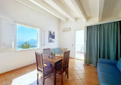 a dining room with a table and chairs and a couch at Solemar Sicilia - Casa Eos in Porticello