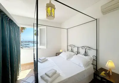 a bedroom with a canopy bed with a view of the ocean at Solemar Sicilia - Casa Eos in Porticello
